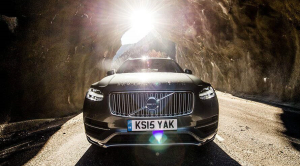 Black Volvo driving through a rocky tunnel